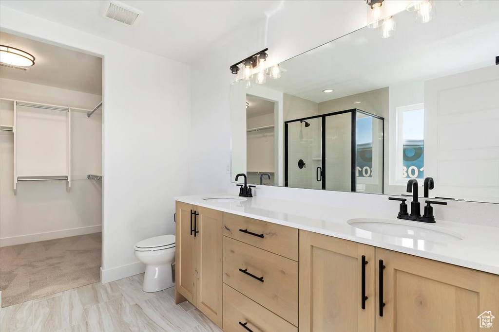 Bathroom featuring walk in shower, vanity, and toilet