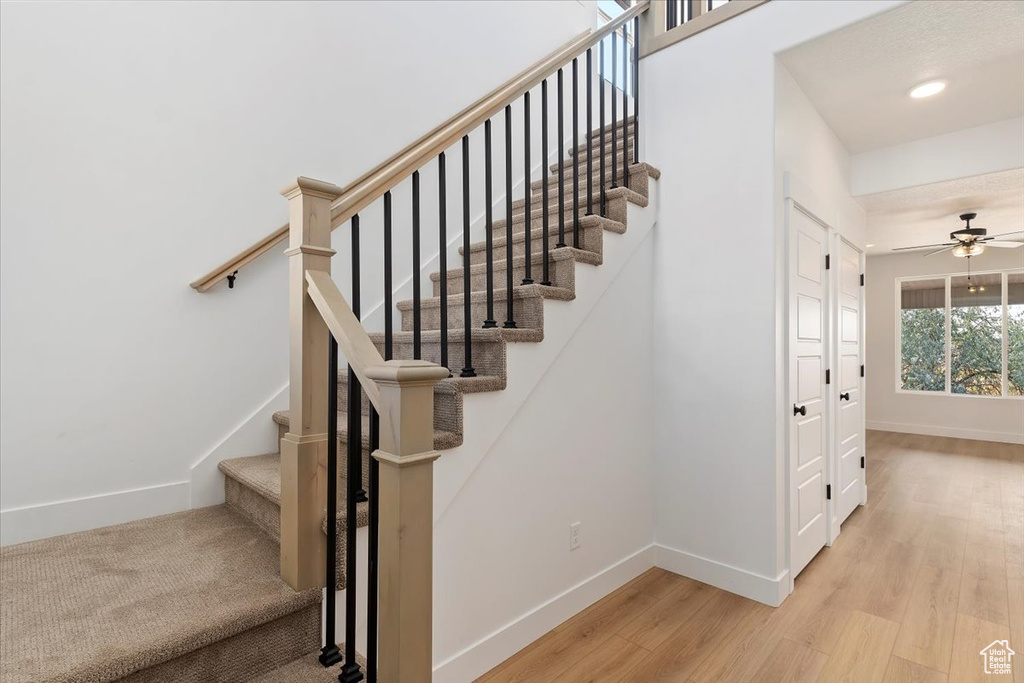 Stairway featuring ceiling fan and hardwood / wood-style floors