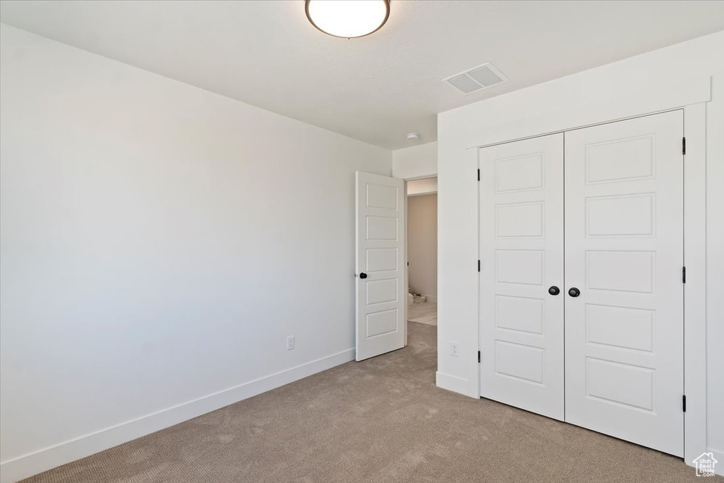 Unfurnished bedroom featuring a closet and light colored carpet