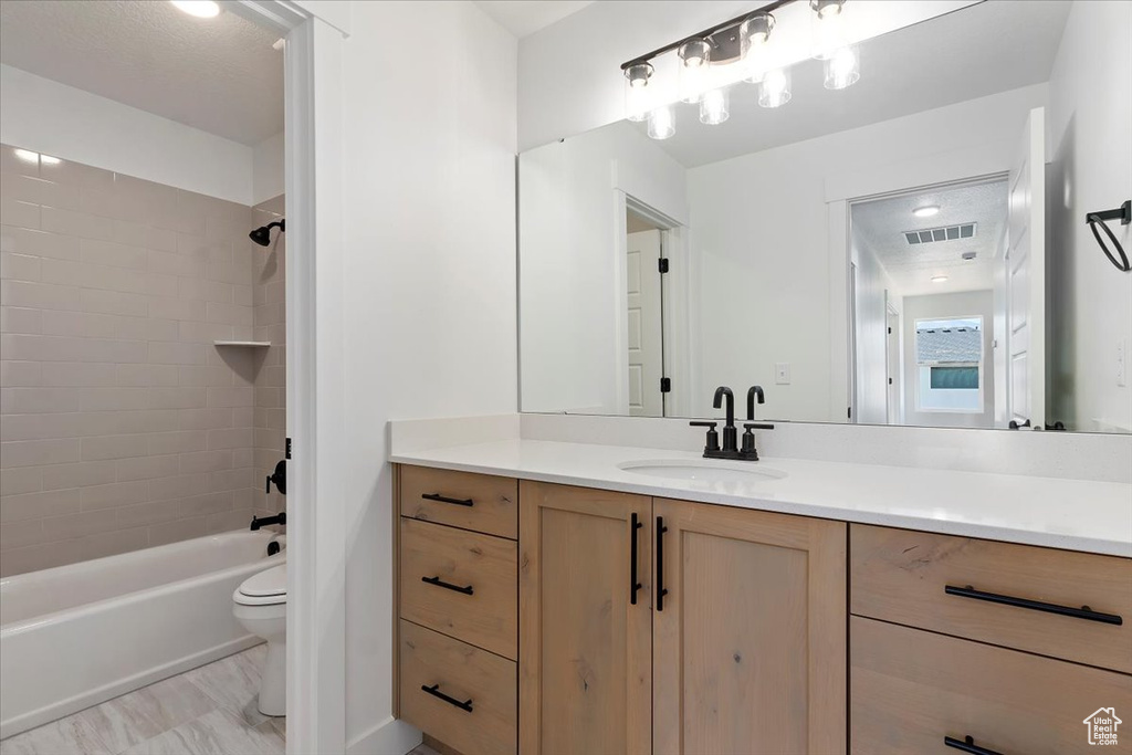 Full bathroom featuring vanity, toilet, and tiled shower / bath combo