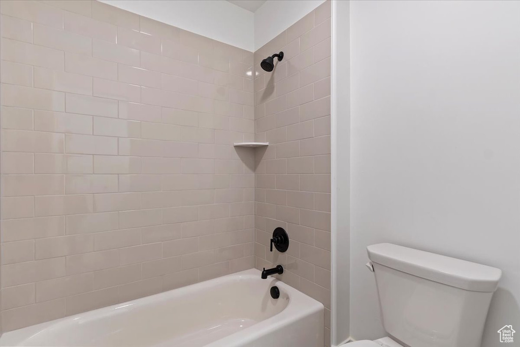 Bathroom with tiled shower / bath and toilet