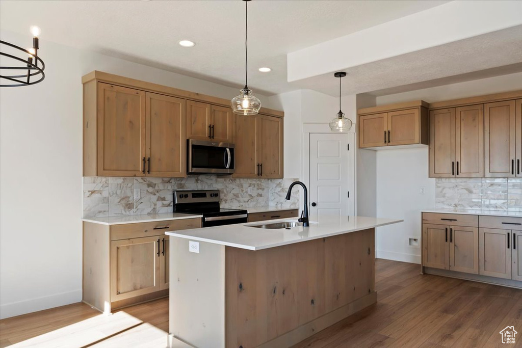 Kitchen featuring a kitchen island with sink, stainless steel appliances, light wood-type flooring, and sink