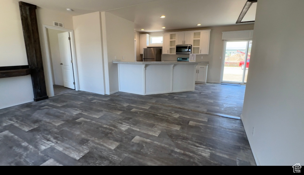 Kitchen with stainless steel appliances, dark hardwood / wood-style floors, kitchen peninsula, and white cabinetry