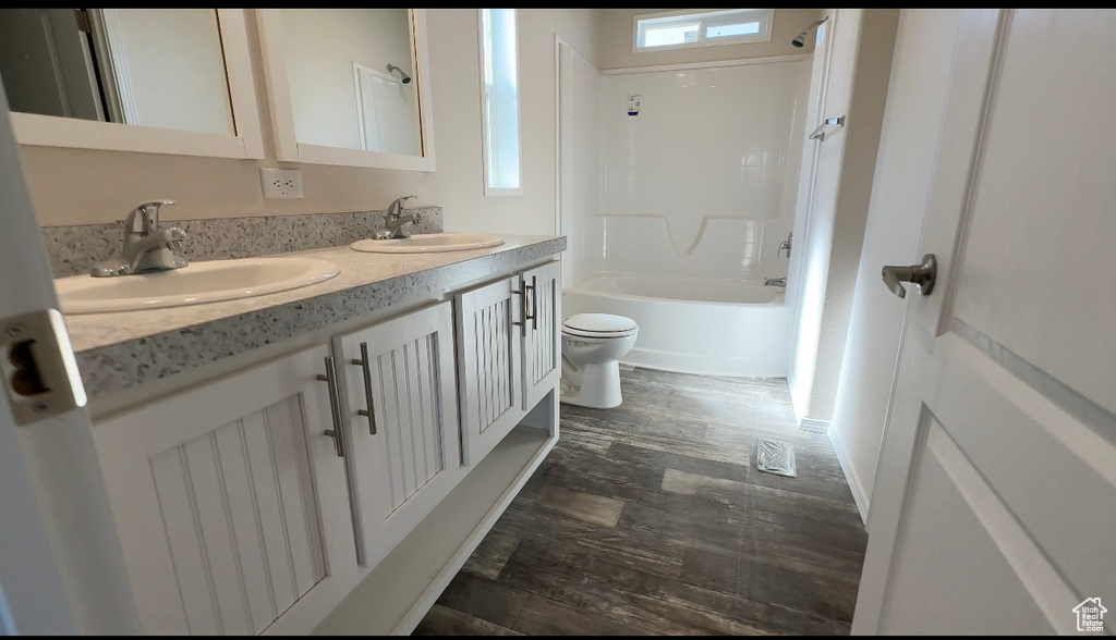 Full bathroom with wood-type flooring, vanity, toilet, and shower / bathtub combination