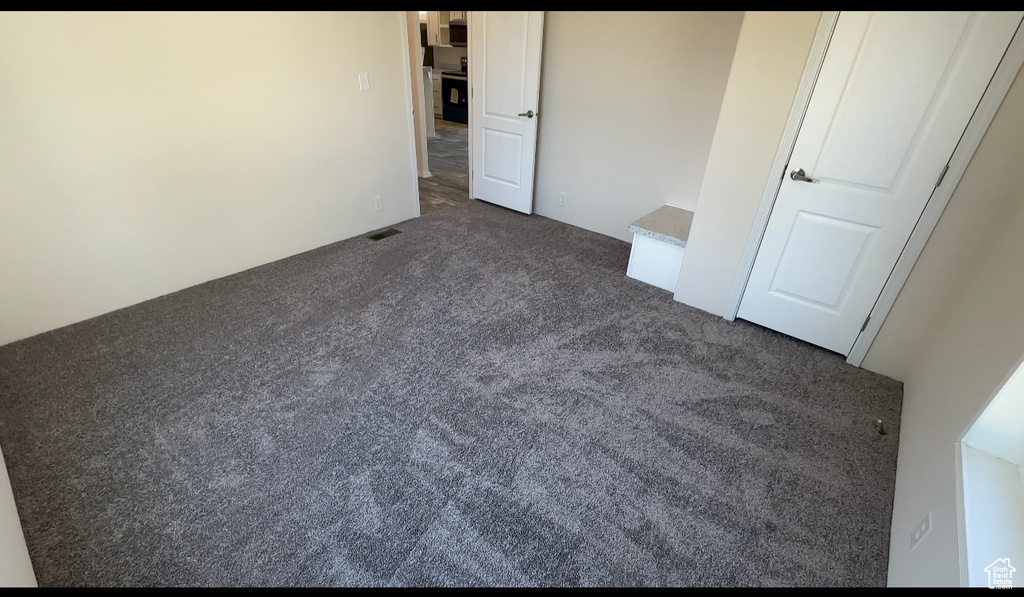 Unfurnished bedroom with dark colored carpet