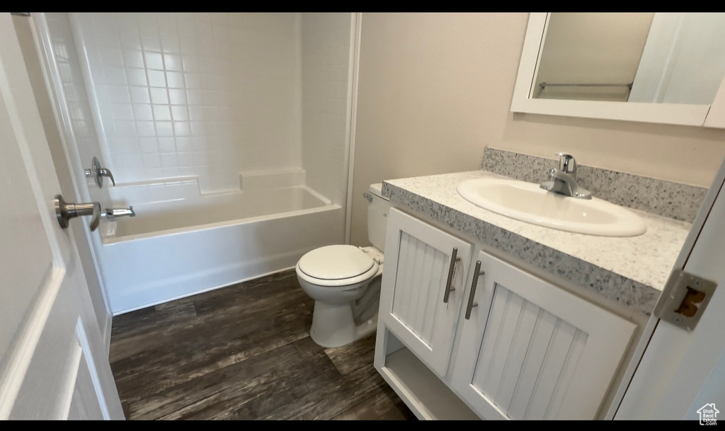 Full bathroom with vanity, shower / bathtub combination, toilet, and hardwood / wood-style flooring