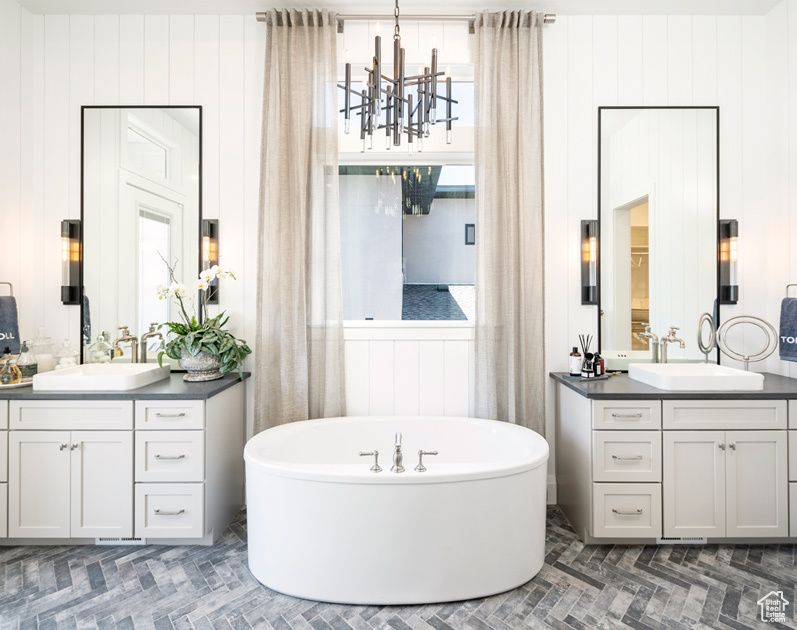 Bathroom featuring a tub to relax in, vanity, and an inviting chandelier