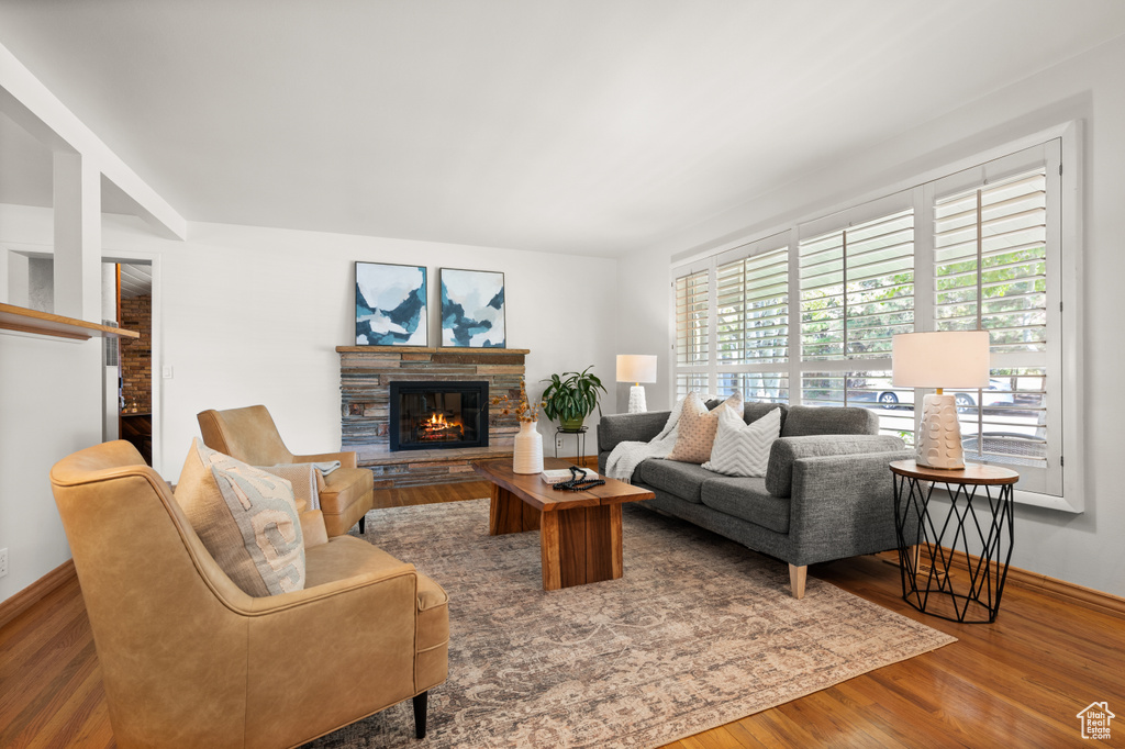 Living room with a stone fireplace and hardwood / wood-style floors