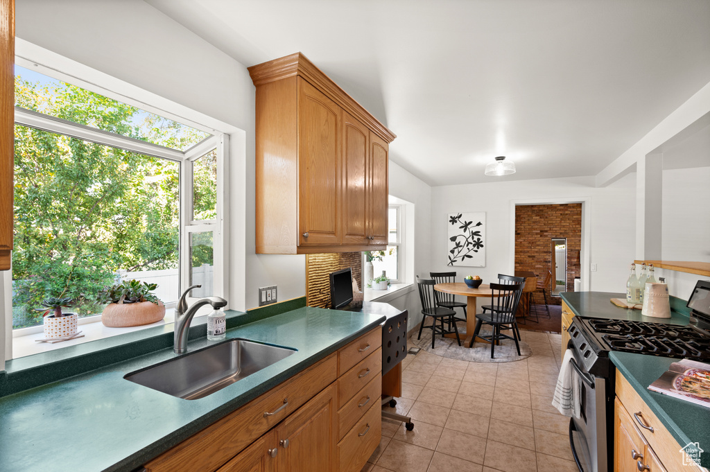 Kitchen with a brick fireplace, light tile patterned floors, sink, and stainless steel gas range