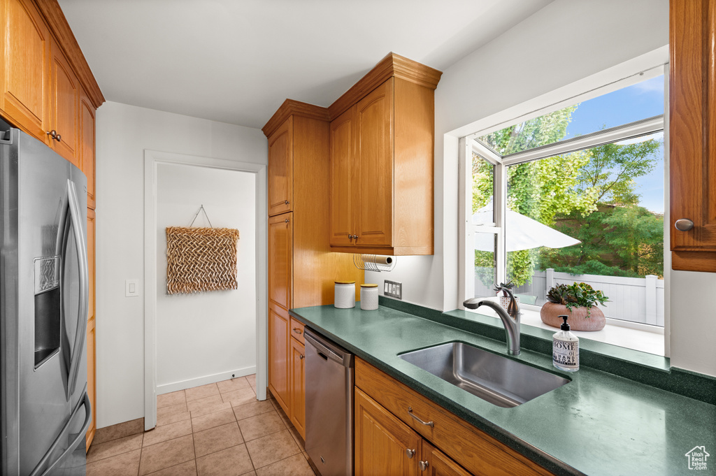 Kitchen featuring light tile patterned floors, stainless steel appliances, and sink