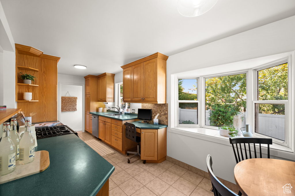 Kitchen with light tile patterned flooring, sink, decorative backsplash, and stainless steel dishwasher