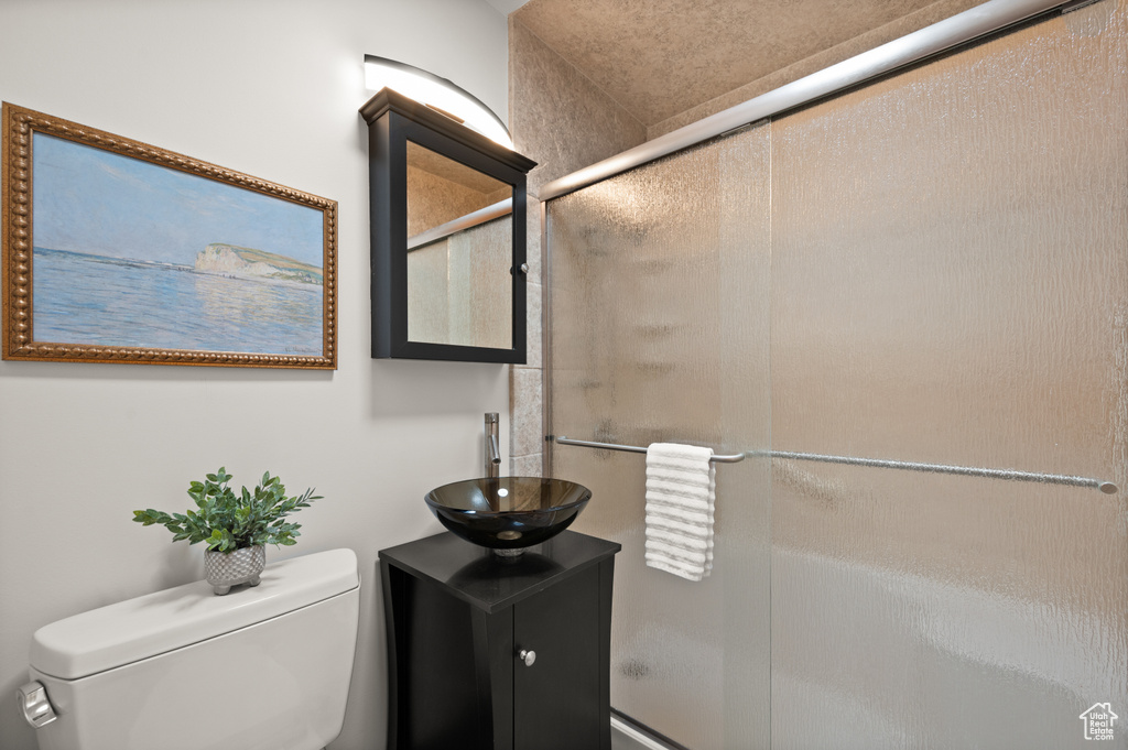 Bathroom featuring vanity, a shower with door, and toilet