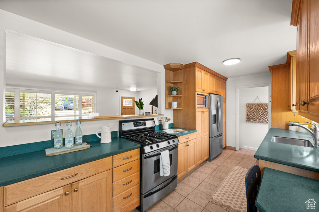 Kitchen with light tile patterned floors, appliances with stainless steel finishes, and sink