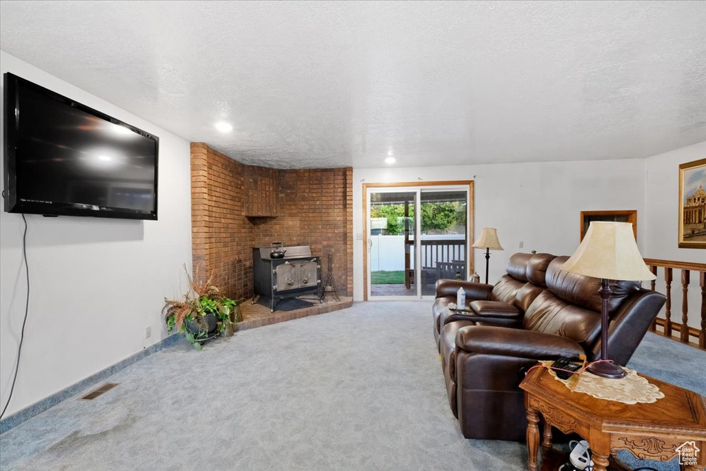 Carpeted living room with a textured ceiling and a wood stove