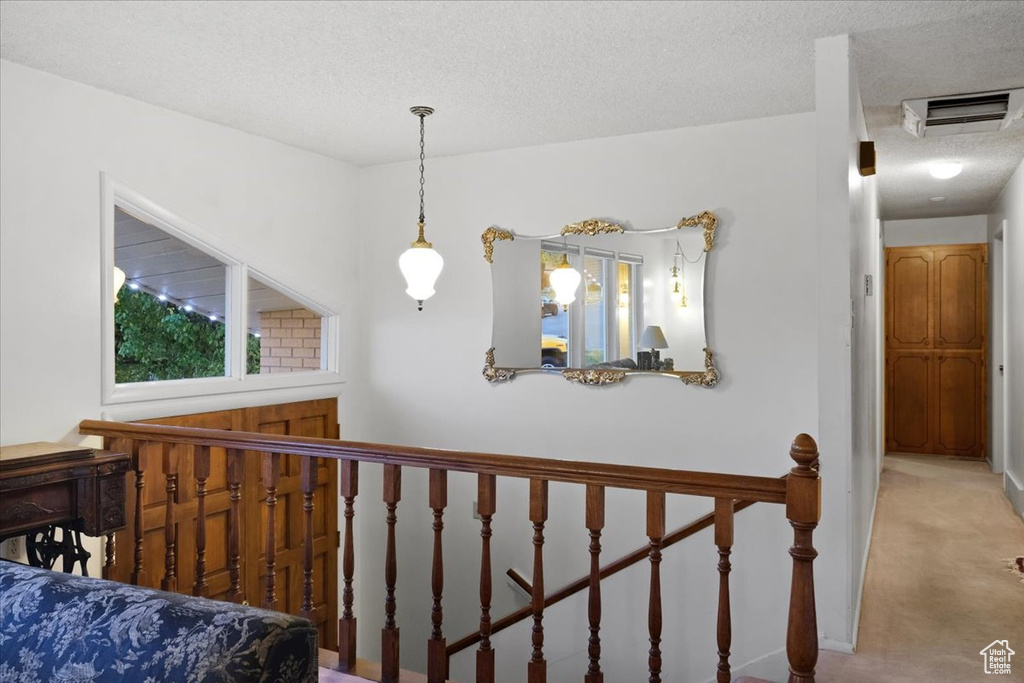 Corridor featuring light colored carpet and a textured ceiling