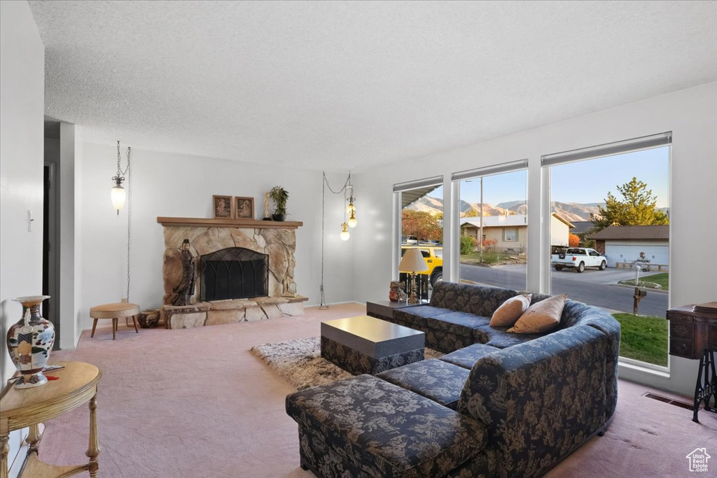 Carpeted living room featuring a stone fireplace and a textured ceiling