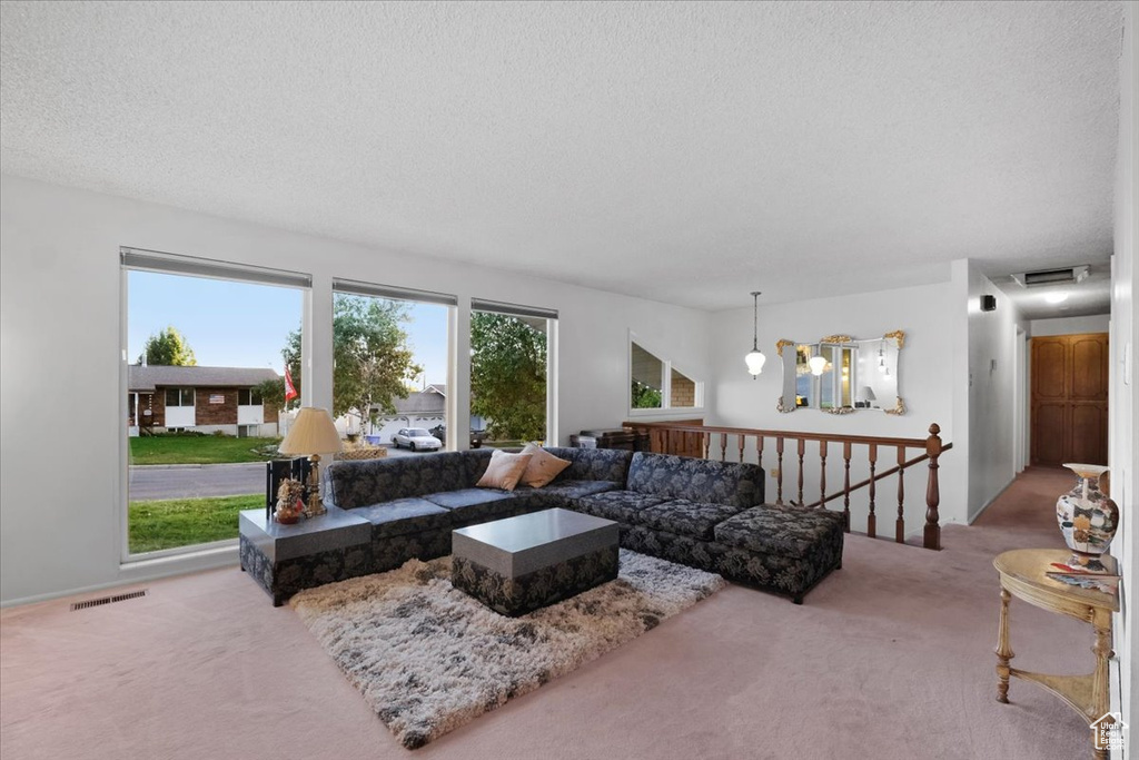 Carpeted living room with an inviting chandelier and a textured ceiling