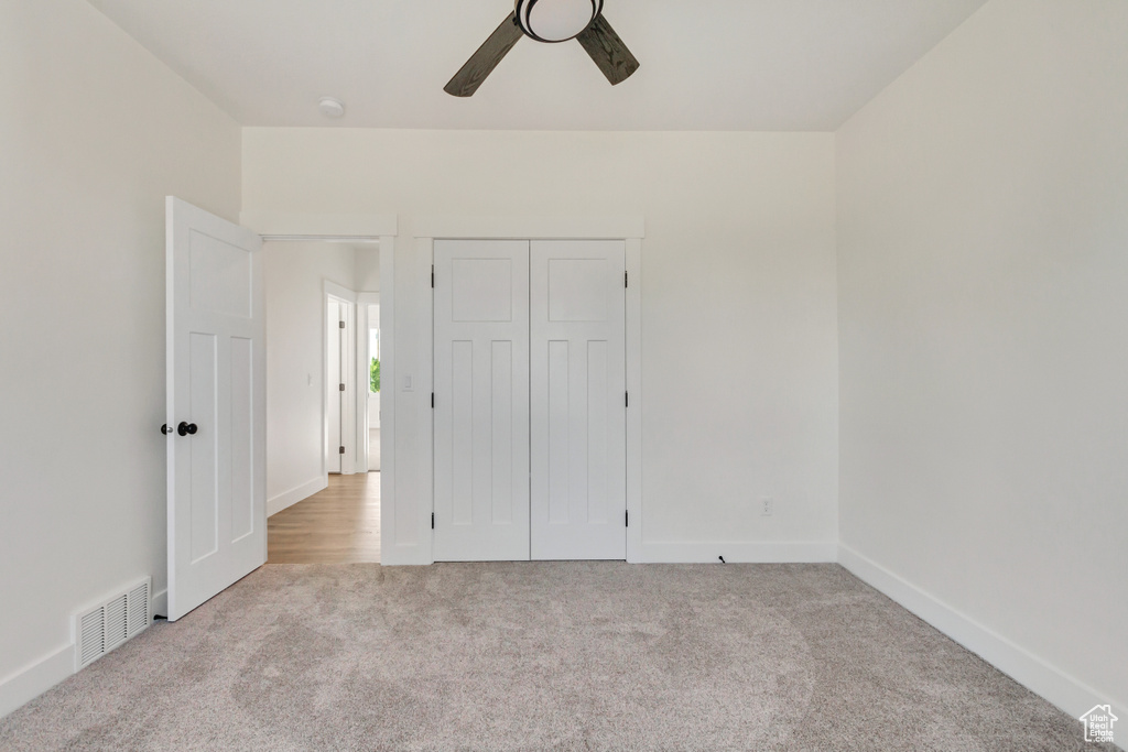 Unfurnished bedroom featuring ceiling fan, light colored carpet, and a closet