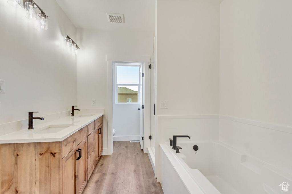 Bathroom featuring a bathtub, vanity, toilet, and hardwood / wood-style floors