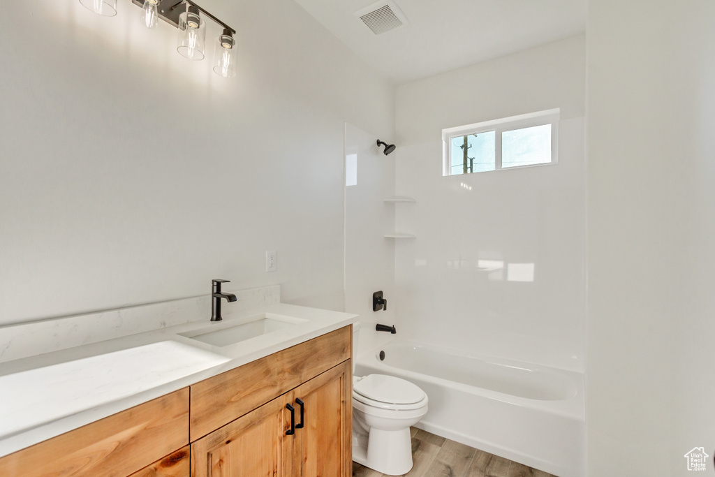 Full bathroom with wood-type flooring, shower / bathing tub combination, vanity, and toilet