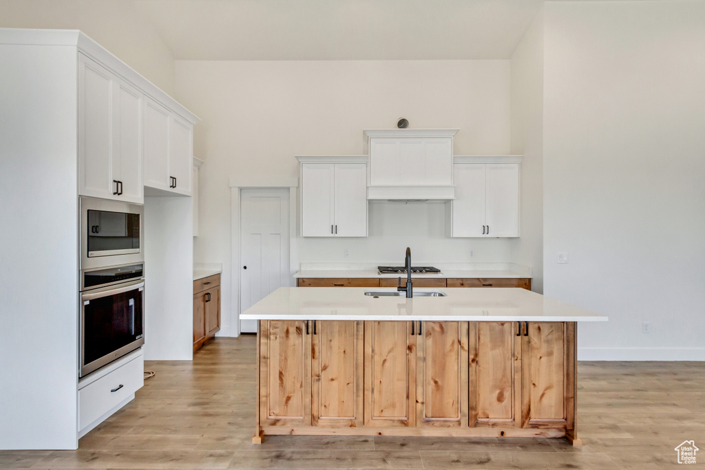 Kitchen with a kitchen island with sink and white cabinetry