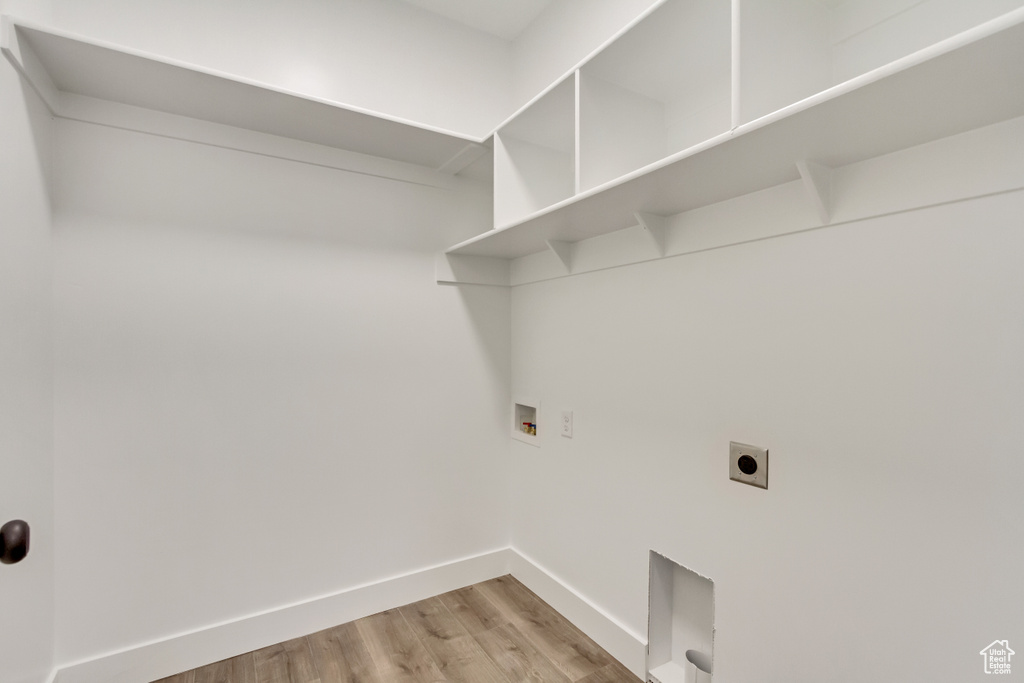 Clothes washing area featuring light wood-type flooring, hookup for a washing machine, and hookup for an electric dryer