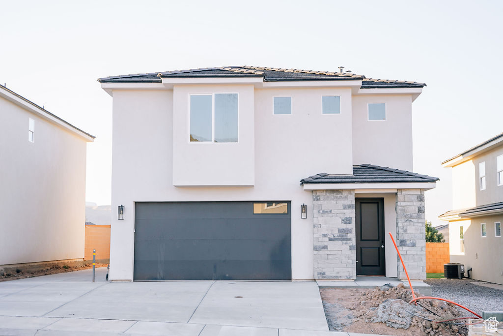 View of front of property featuring central air condition unit and a garage