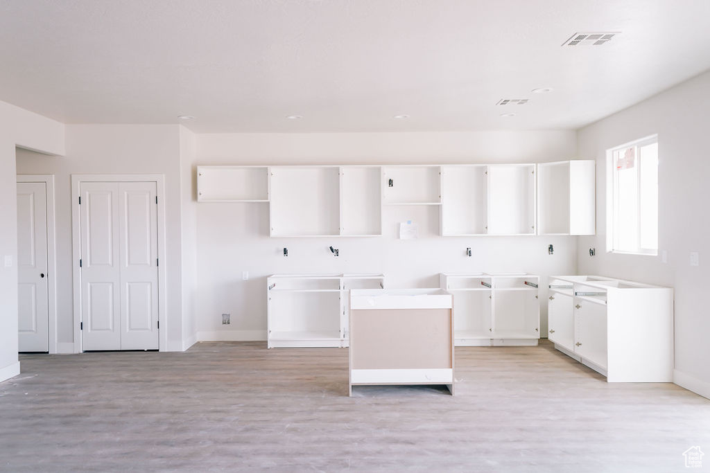 Kitchen featuring white cabinets, a kitchen island, and light wood-type flooring