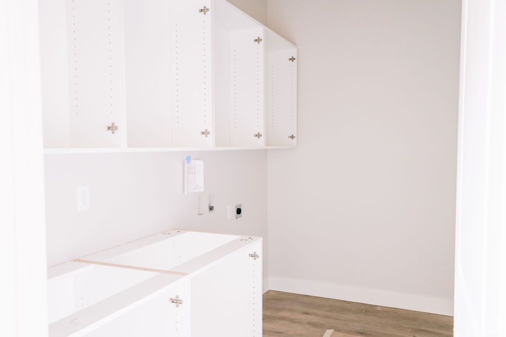 Laundry area featuring hardwood / wood-style floors, cabinets, and electric dryer hookup