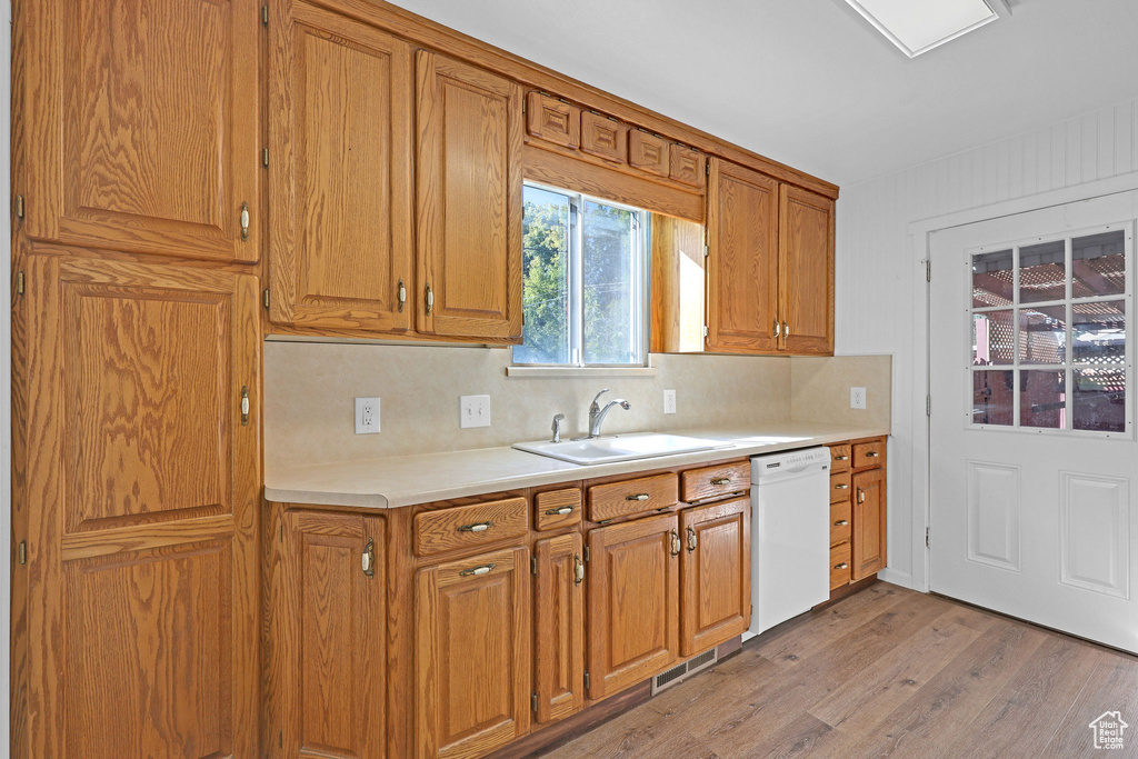 Kitchen featuring light hardwood / wood-style floors, tasteful backsplash, sink, and white dishwasher