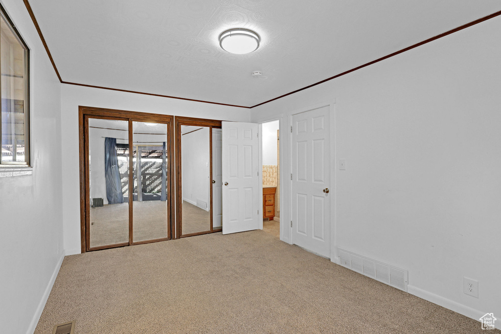 Unfurnished bedroom with multiple windows and light colored carpet