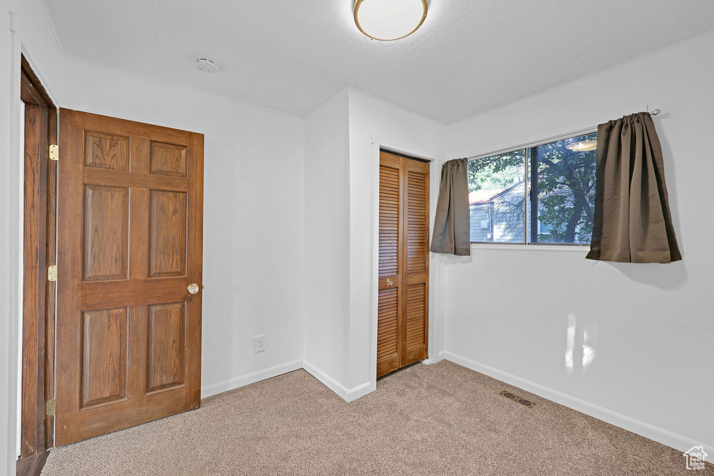 Unfurnished bedroom featuring a closet and light colored carpet