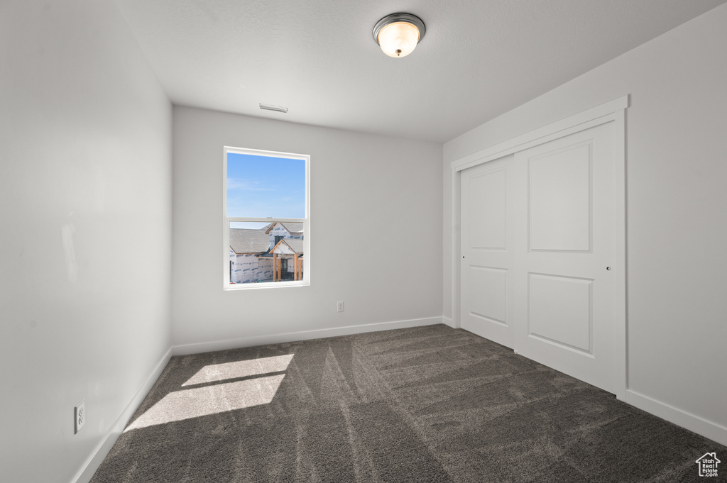 Unfurnished bedroom featuring a closet and dark colored carpet