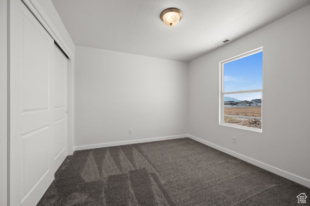 Unfurnished bedroom featuring a mountain view, a closet, and dark colored carpet