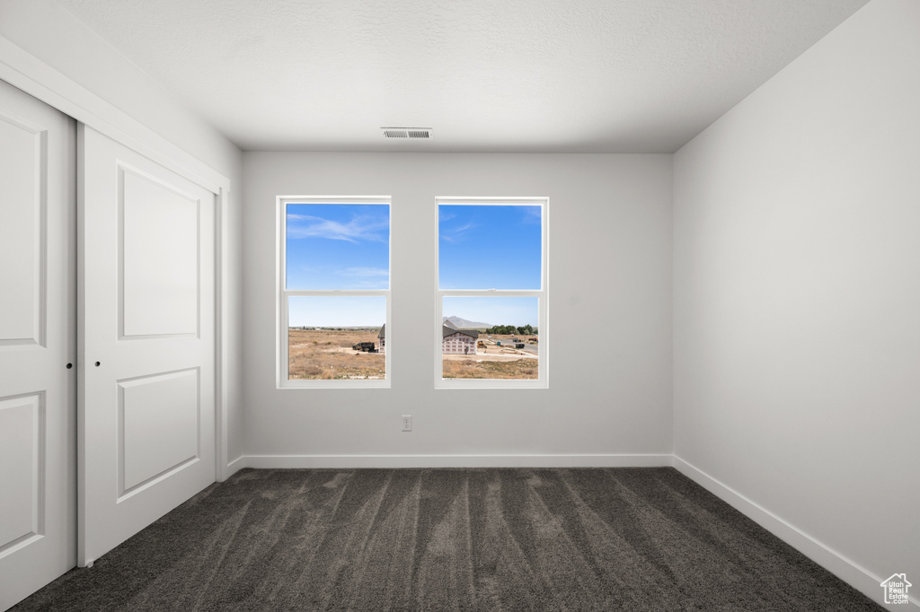 Spare room featuring dark carpet