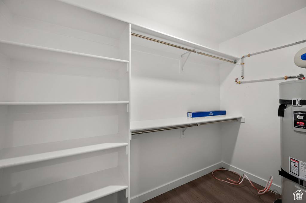 Walk in closet featuring dark wood-type flooring and secured water heater