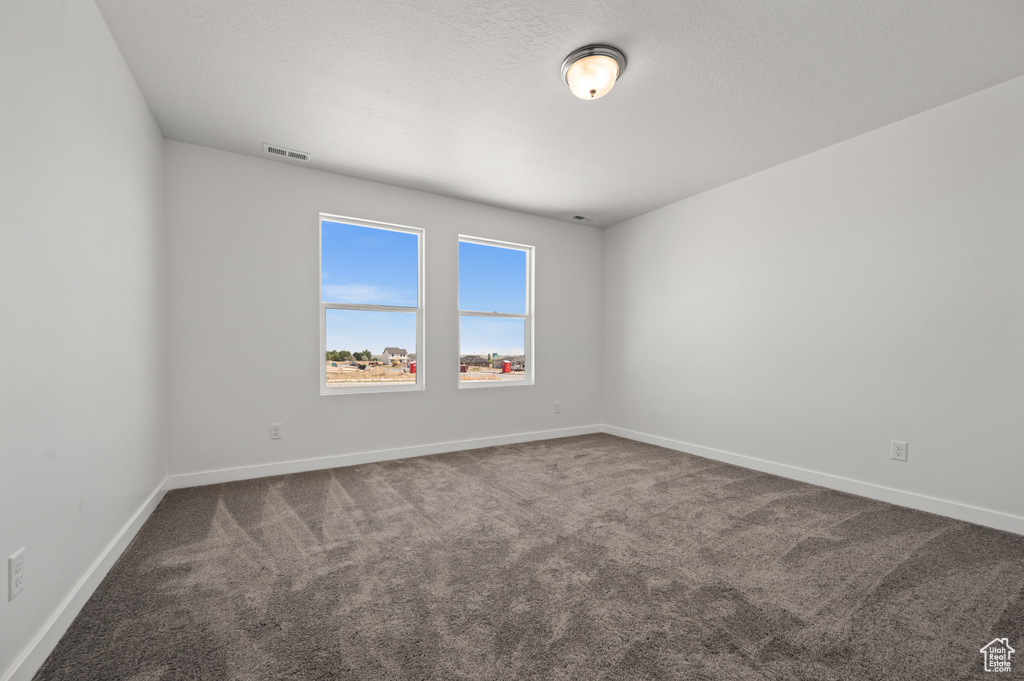 Empty room with carpet floors and a textured ceiling