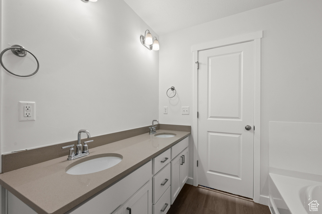 Bathroom with wood-type flooring, a tub, and vanity