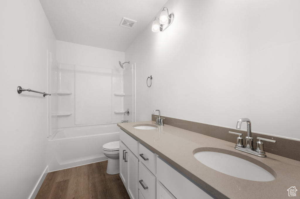 Full bathroom featuring washtub / shower combination, wood-type flooring, vanity, and toilet