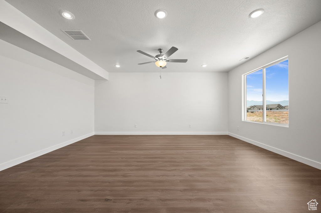 Empty room featuring a textured ceiling, a mountain view, and dark hardwood / wood-style flooring