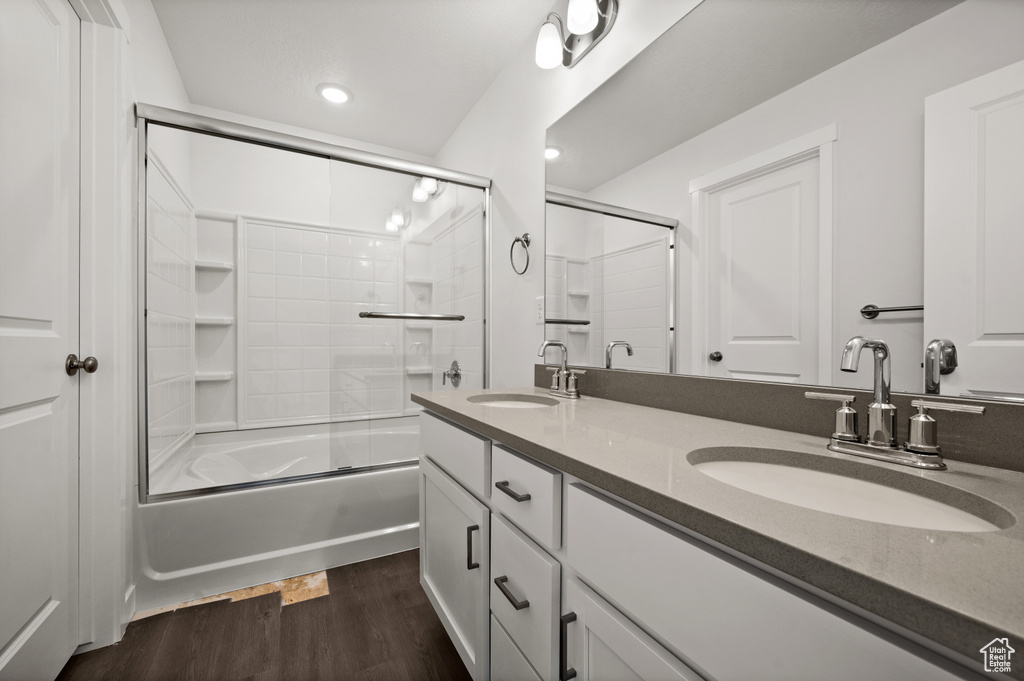 Bathroom featuring combined bath / shower with glass door, hardwood / wood-style flooring, and vanity