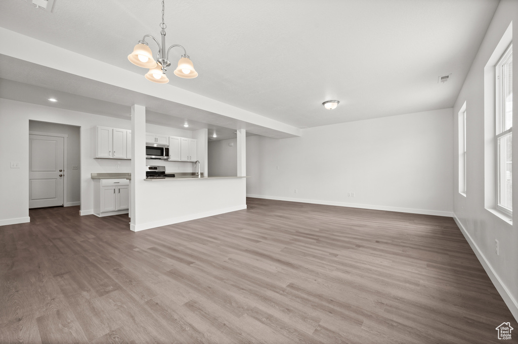 Unfurnished living room featuring sink, a chandelier, and hardwood / wood-style floors