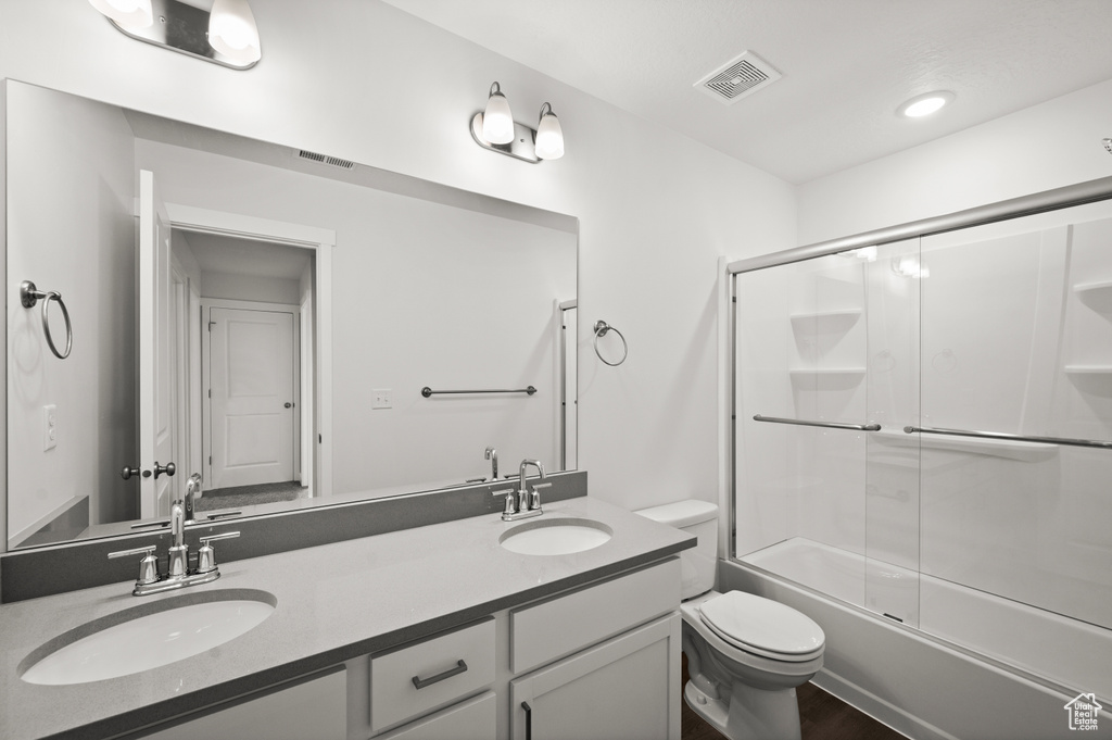 Full bathroom with combined bath / shower with glass door, toilet, and vanity