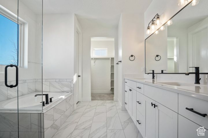 Bathroom featuring tiled tub and vanity