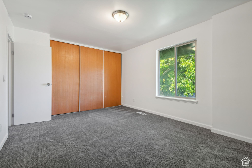 Unfurnished bedroom featuring dark colored carpet and a closet