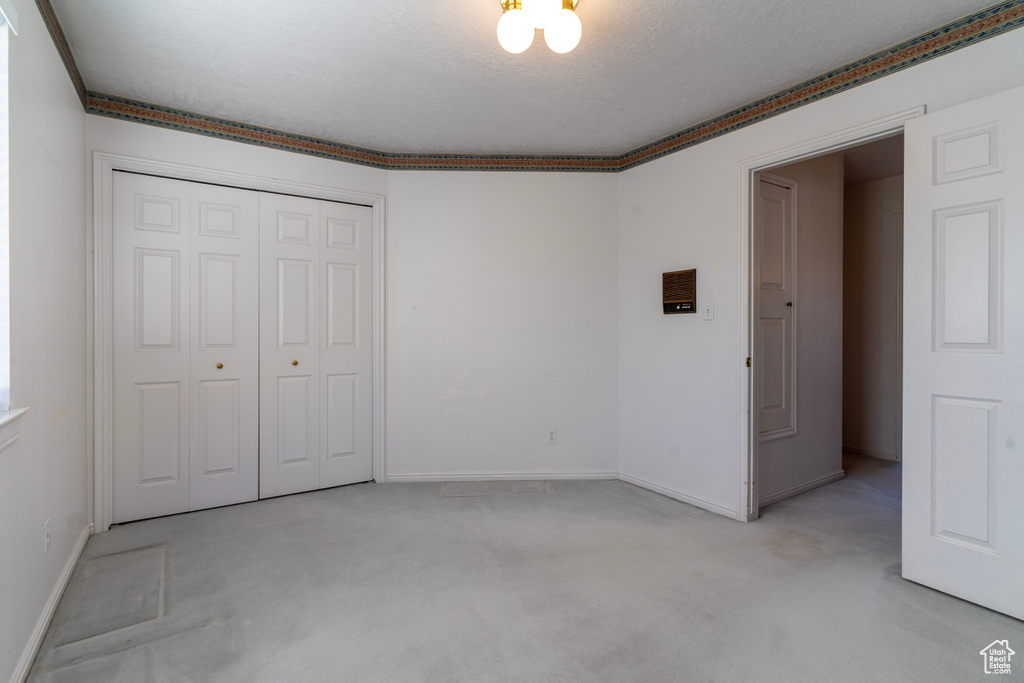 Unfurnished bedroom with light carpet, a textured ceiling, and a closet