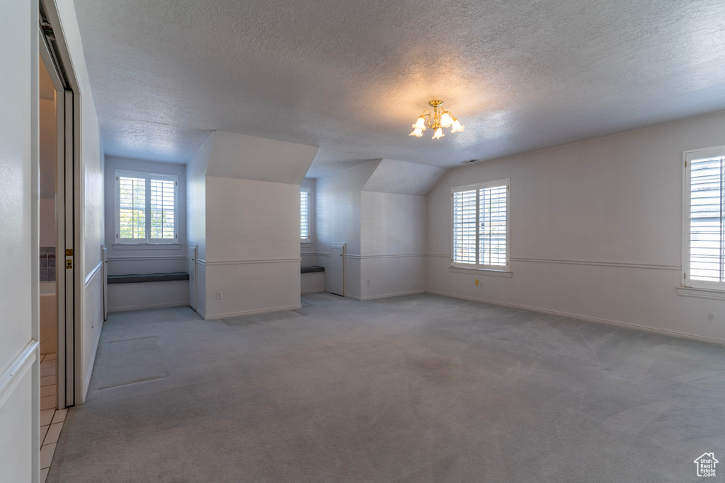 Additional living space with plenty of natural light, light colored carpet, and a textured ceiling