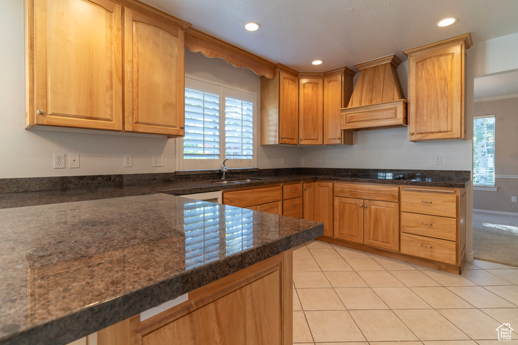 Kitchen with light tile patterned floors, custom exhaust hood, crown molding, and sink