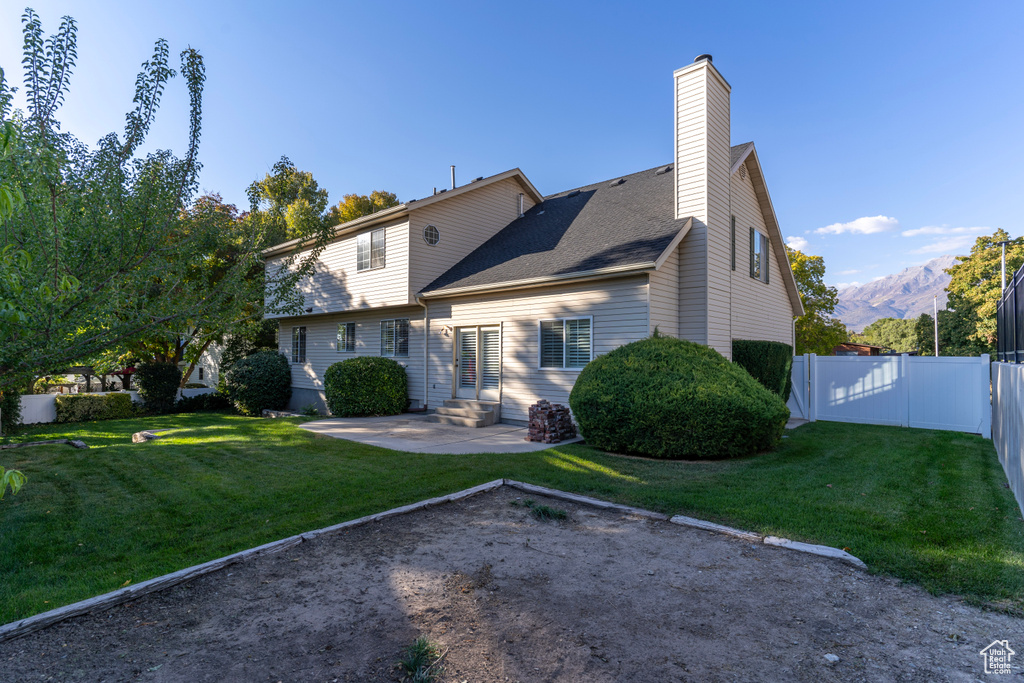 Back of house with a yard, a patio area, and a mountain view