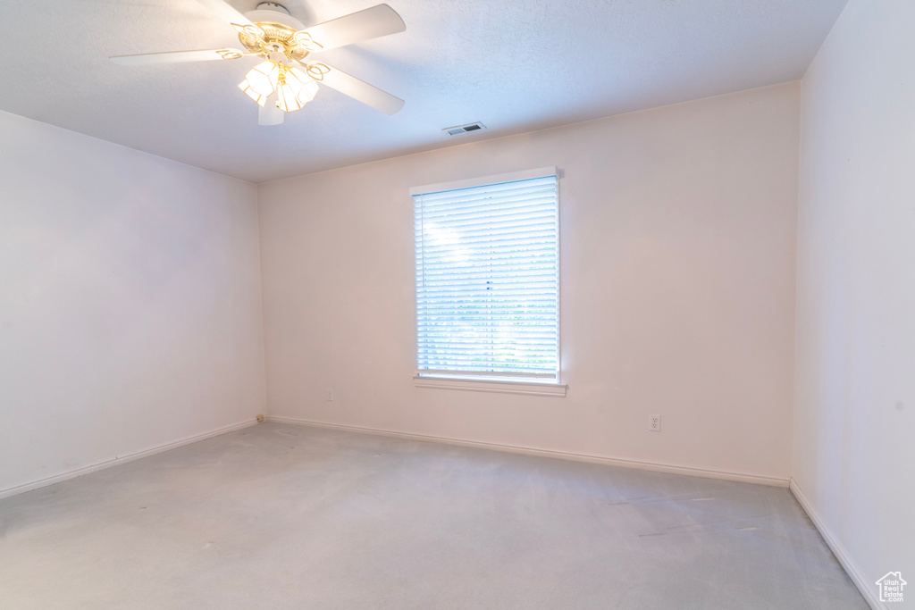 Carpeted empty room featuring ceiling fan